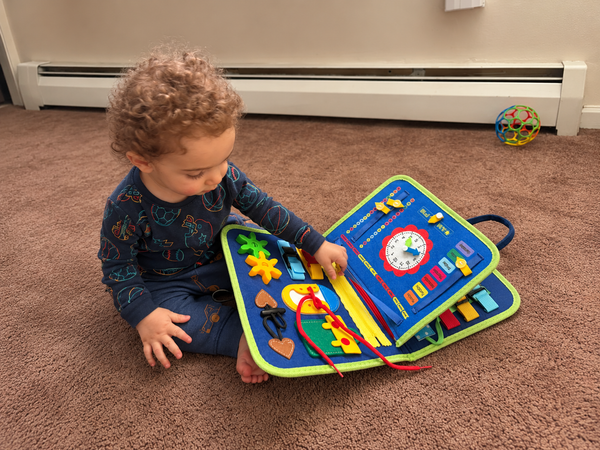Toddler hands working a real buckle on the busy board